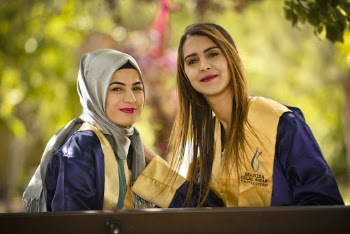 Selective Focus Portrait Photo of Smiling Women in Academic Regalia Posing