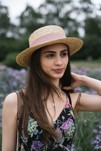 Selective Focus Portrait Photo of Woman in Sun Hat and Floral Dress Standing in Flower Field