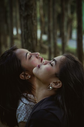 Selective Focus Portrait Photo of Women Posing with their Heads Up and Eyes Closed