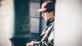 Selective Focus Side View Photo of Sitting Man in Red Hat and Gray Jacket