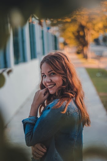 Selective Focus Side View Photo of Smiling Woman Standing on Side Walk Posing 