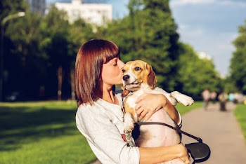 Selective Focus Side View Photo of Woman Kissing a Dog While Carrying it