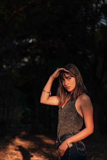 Selective Focus Side View Photo of Woman Wearing Gray Blouse and Blue Jeans Posing