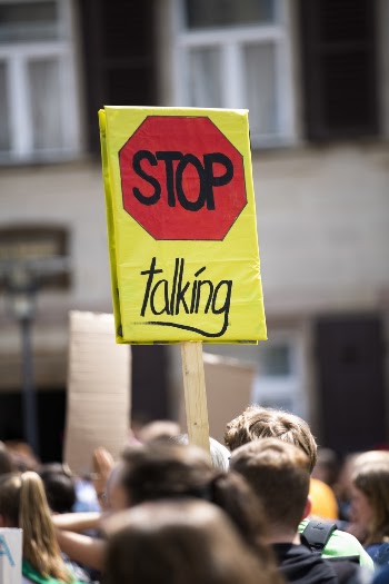 Selective Photo of Stop Talking Sign Carried by People Walking on Street