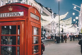 selective photography of red telephone booth under blue sky at night