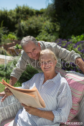 Senior couple reading newspaper in sunny garden