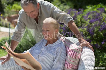 Senior couple reading newspaper in sunny garden