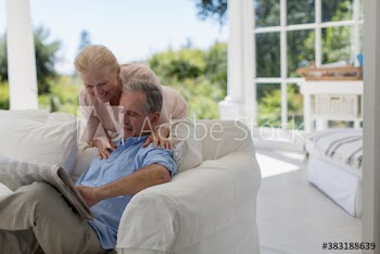 Senior couple reading newspaper on patio sofa