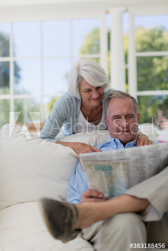 Senior couple reading newspaper on sofa