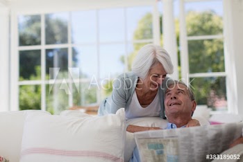 Senior couple reading newspaper on sofa