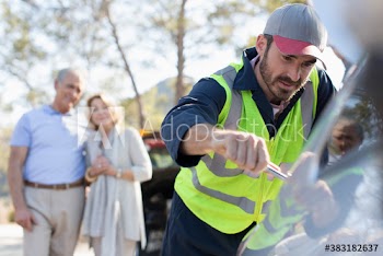 Senior couple watching male roadside assistance mechanic fix car