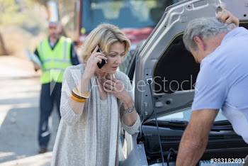 Senior couple with smart phone at roadside with car breakdown