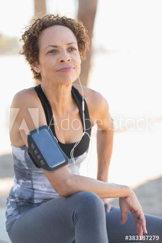 Senior female runner with armband and headphones resting