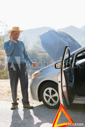 Senior man calling for car breakdown help at sunny roadside