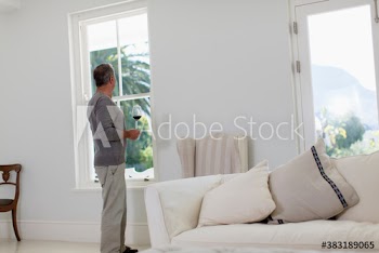 Senior man drinking red wine and looking out living room window