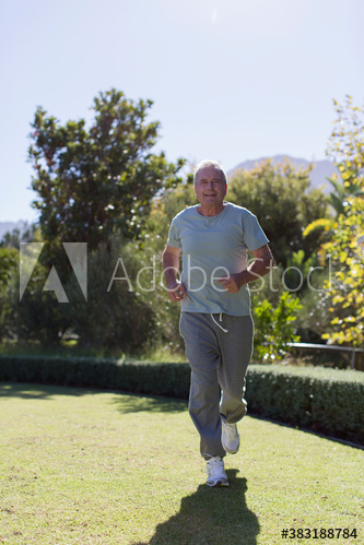 Senior man jogging in sunny garden