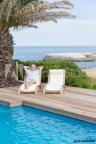 Senior man relaxing in lounge chair at ocean poolside