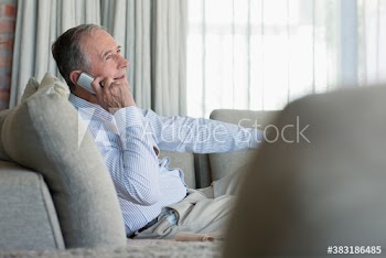 Senior man talking on mobile phone on sofa