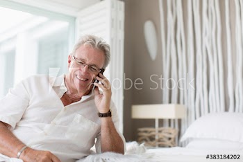 Senior man talking on smart phone on bed