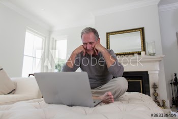 Senior man using laptop on living room ottoman