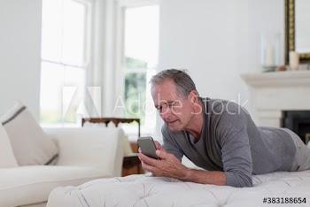 Senior man using smart phone on ottoman