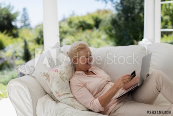Senior woman online shopping with credit card and laptop on sofa