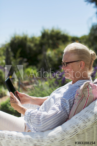 Senior woman using digital tablet in sunny garden