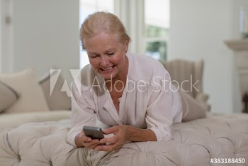 Senior woman using smart phone on ottoman