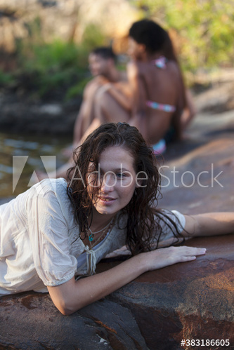 Sensual young woman relaxing on wet rocks