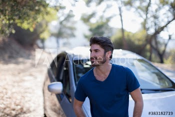 Serene man sitting on on car at sunny roadside
