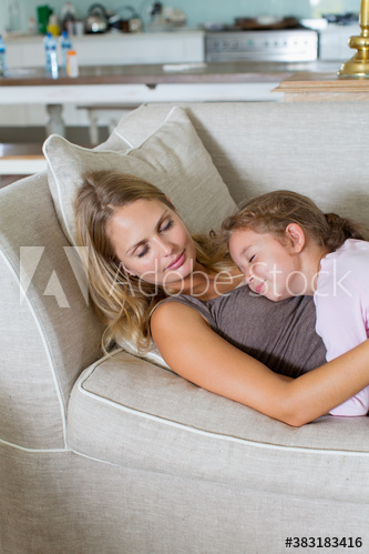 Serene mother and daughter cuddling on sofa