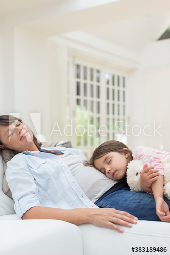 Serene pregnant mother and daughter cuddling on sofa