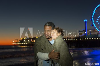 Serene senior couple hugging on beach at night, Santa Monica, USA