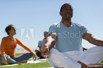 Serene senior man practicing yoga meditation on sunny lawn