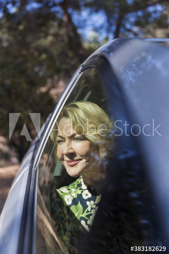 Serene senior woman looking out sunny car window