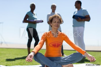 Serene senior woman practicing yoga meditation in sunny grass
