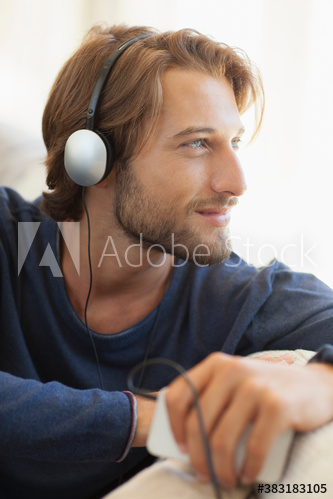 Serene young man listening to music with headphones and mp3 player