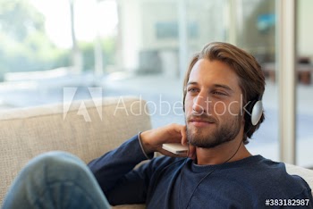 Serene young man listening to music with headphones on sofa