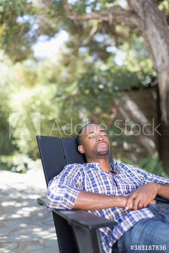 Serene young man relaxing in chair on patio