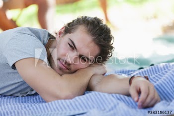 Serene young man relaxing on picnic blanket