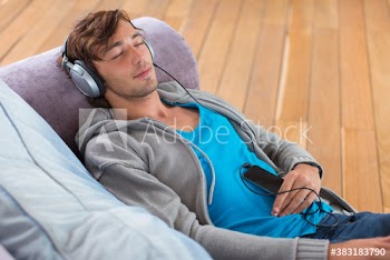 Serene young man relaxing on sofa listening to music with headphones