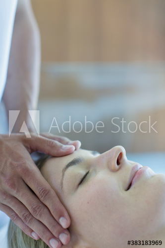 Serene young woman receiving head massage in spa