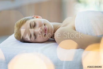 Serene young woman relaxing on spa massage table