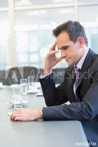 Serious corporate businessman reading paperwork in conference room