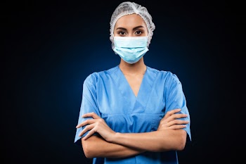 Serious doctor in medical mask and cap looking Free Photo