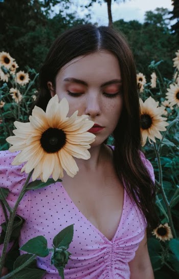Serious pensive woman near flower in meadow · Free Stock Photo