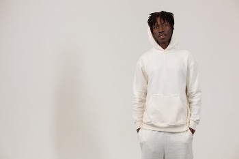 Serious young black male in stylish outfit standing in white studio