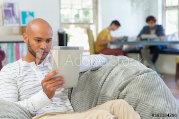 Serious young man using digital tablet in beanbag chair