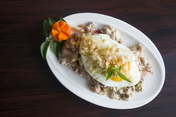 Serving of Marinated Meat With Sunny Side-up Egg and Slice of Carrot in Oval White Ceramic Plate