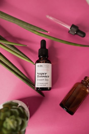 Set of bottles with face serum on pink surface